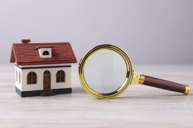 Ev araması. Büyüteç ve ev modeli ahşap masada.