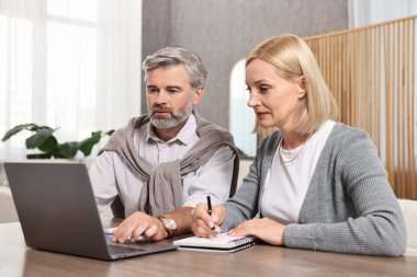 Couple planning pension budget at table indoors clipart