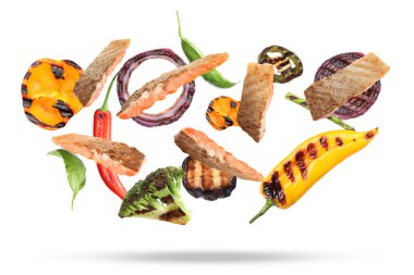 Lezzetli ızgara somon ve beyaz arka plana düşen sebzeler.