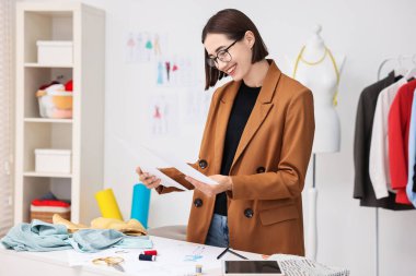 Moda tasarımcısı atölyede çizimler yapıyor.