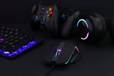 Bilgisayar faresi, kulaklık, RGB klavye ve oyun denetleyicileri siyah arkaplanda, yakın plan