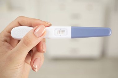 Kapalı alanda pozitif hamilelik testi tutan kadın, yakın çekim.