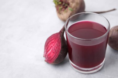 Bardakta taze pancar suyu ve gri masada olgun sebzeler, yakın plan. Metin için boşluk