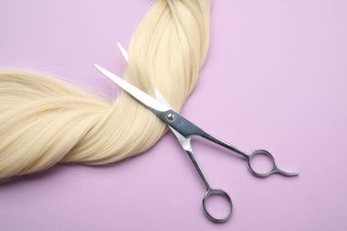 Sarı saç teli ve profesyonel makas menekşe arka planda, üst görünüm