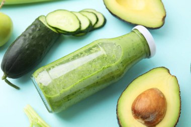 Şişede lezzetli yeşil smoothie ve açık mavi arka planda ürünler, yakın plan