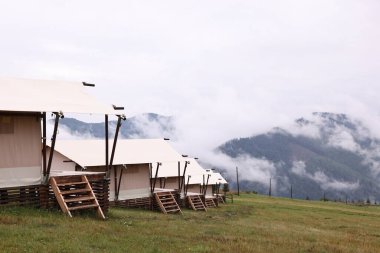 Dağlarda sisle kaplı bir sürü çadır ve orman var. Glamping alanı