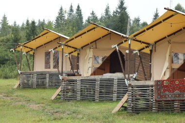 Dağlarda bir sürü çadır ve yeşil orman. Glamping alanı