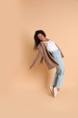 Bej arka planda şık ceketli güzel bir kadın.