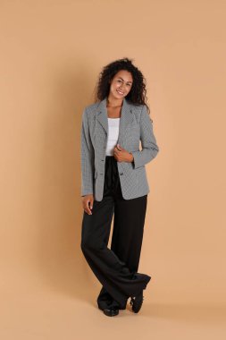 Bej arka planda şık ceketli güzel bir kadın.