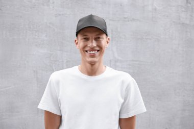 Işık duvarının yanında beyzbol şapkalı gülümseyen adamın portresi.