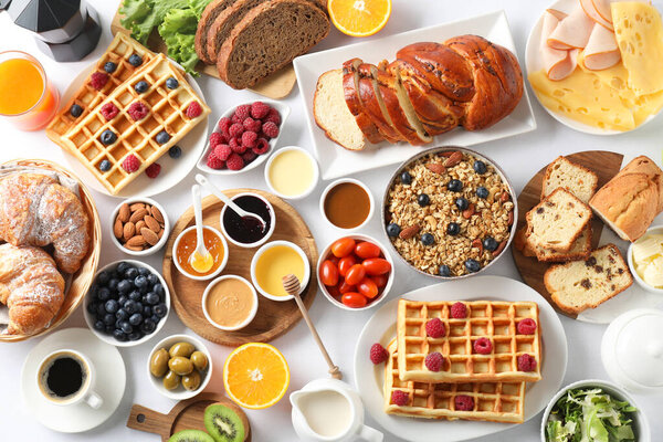 Different meals served for breakfast on white table, flat lay