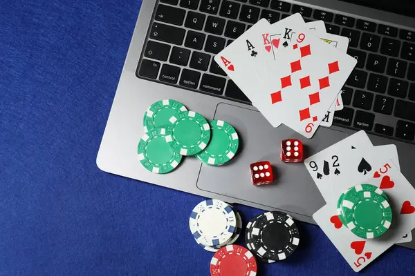 Poker fişleri, dizüstü bilgisayar, kağıt ve zarlar mavi masada, düz konum. Çevrimiçi oyun