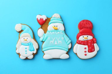 Açık mavi arka planda kardan adam şeklinde lezzetli Noel kurabiyeleri.