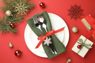 Tabakları, şık çatal bıçakları ve kırmızı masa üzerindeki şenlikli dekorları olan güzel bir Noel ortamı.