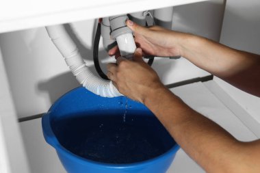 Profesyonel tesisatçı evdeki boru sistemini tamir ediyor.