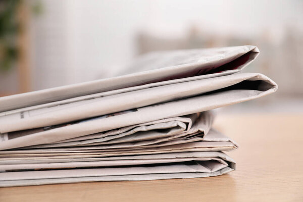 Stack of newspapers in different languages on table indoors, closeup