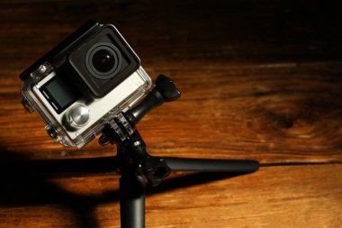 Ahşap yüzeyde modern aksiyon kamerası ve tripod. Metin için boşluk