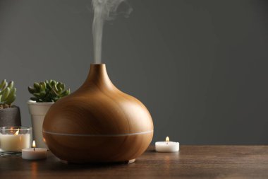 Aroma yağı yayıcı, ev bitkileri ve yanan mumlar ahşap masa, metin için yer