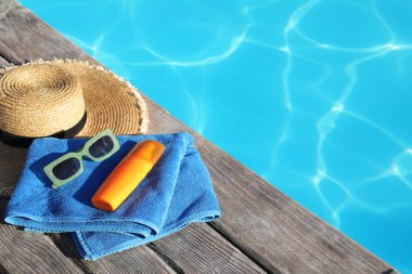 Güneş gözlüğü, havlu, şapka ve güneş kremi açık havuz kenarında. Metin için boşluk