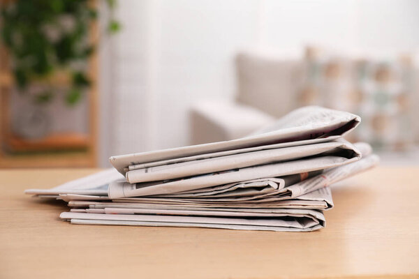 Stack of newspapers in different languages on table indoors