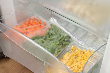 Buzdolabında farklı donmuş sebzeler olan plastik poşetler.