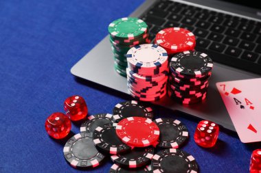 Poker fişleri, laptop, iskambil kağıtları ve zarlar mavi masada. Çevrimiçi oyun
