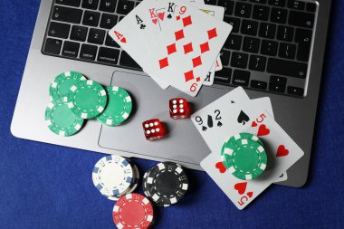Poker fişleri, dizüstü bilgisayar, kağıt ve zarlar mavi masada, düz konum. Çevrimiçi oyun