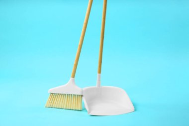 Açık mavi arkaplanda süpürge ve faraş temizleniyor
