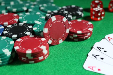 Poker fişleri ve iskambil kartları yeşil masada, yakın plan.