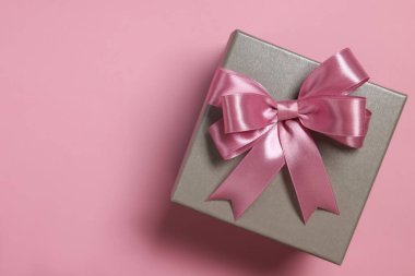 Tozlu pembe arka planda fiyonklu hediye kutusu, üst manzara