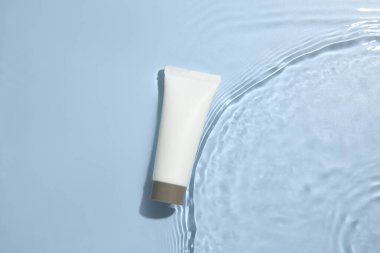 Kozmetik ürünü. Açık mavi arkaplanda kremalı tüp, üst görünüm