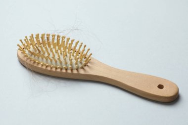 Gri arka planda saçı dökülmüş bir fırça. Alopecia sorunu