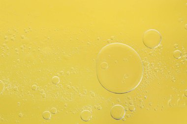 Sarı arka planda gerekli yağ kabarcıkları, makro görünüm. Kozmetik ürünü