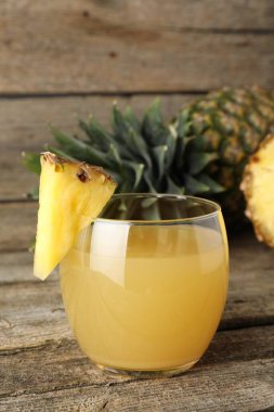 Bardakta nefis ananas suyu ve ahşap masada taze meyve, yakın plan.