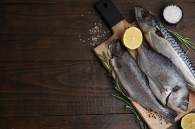 Deniz ürünleri. Farklı çiğ balık türleri, ahşap masada biberiye ve limon, düz yatak. Metin için boşluk