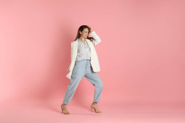 Pembe arka planda şık beyaz ceketli güzel bir kadın.