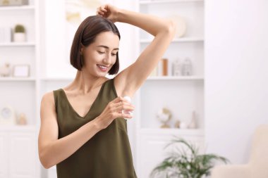 Gülümseyen kadın evde deodorant sürüyor. Metin için boşluk