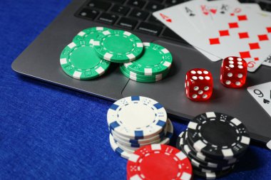 Poker fişleri, dizüstü bilgisayar, mavi masada kağıt ve zarlar. Çevrimiçi oyun