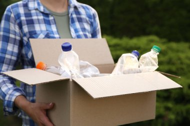 Geri dönüşüm. Elinde plastik şişelerle karton kutu tutan kadın, yakın plan.