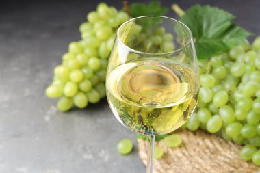 Taze üzümler ve bir kadeh şarap. Gri masada, yakın plan.