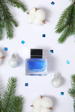 Beyaz arka planda parfüm şişesi olan Noel kompozisyonu.