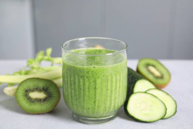Lezzetli yeşil smoothie ve malzemeler ışık masasında, yakın çekim