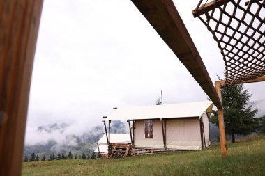 Çadırlar, ağ hamak ve dağlarla kaplı orman, alçak açı. Glamping alanı