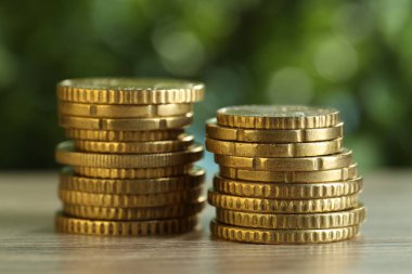 Bulanık yeşil arka plana karşı açık ahşap masaya istiflenmiş bozuk paralar, yakın plan. Maaş kavramı