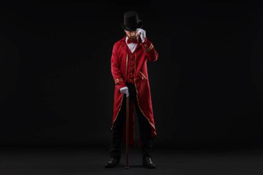 Kırmızı kostümlü ve siyah şapkalı bir şovmen portresi.