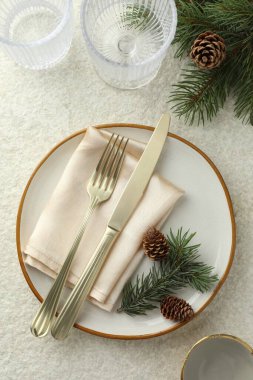 Tabaklı, gözlüklü, çatal bıçaklı, köknar dallı ve konili Noel sofrası.