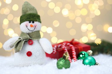 Komik kardan adam figürü, Noel baloları, hediye kutusu ve bulanık ışıklara karşı yapay kar üzerinde şeker kamışları.