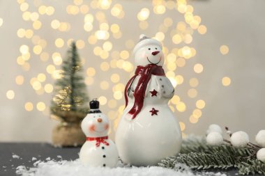 Masadaki bulanık ışıklara karşı komik kardan adam figürü ve diğer dekorlar