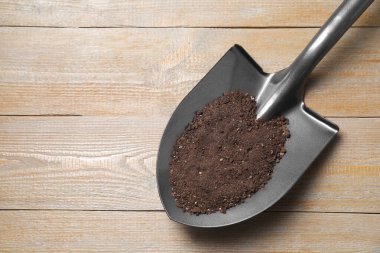 Ahşap masa üzerinde toprak olan metal kürek, üst manzara. Metin için boşluk