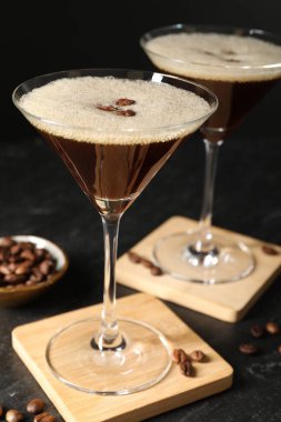 Bir bardak nefis espresso martini ve koyu dokulu masada kahve çekirdekleri.